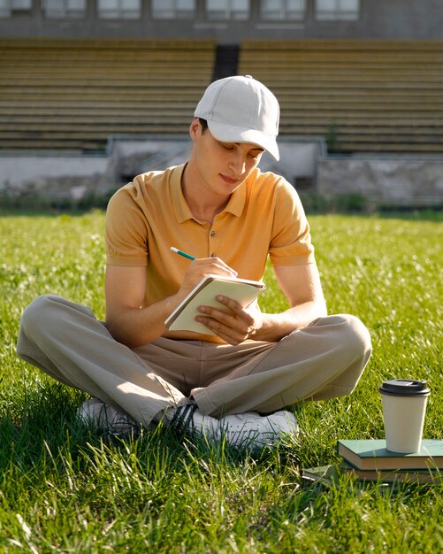 Vista frontal hombre tomando notas al aire libre