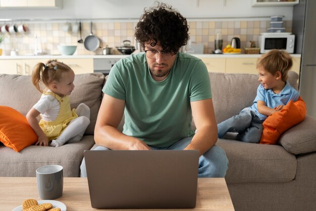 Vista frontal hombre trabajando en casa con niños