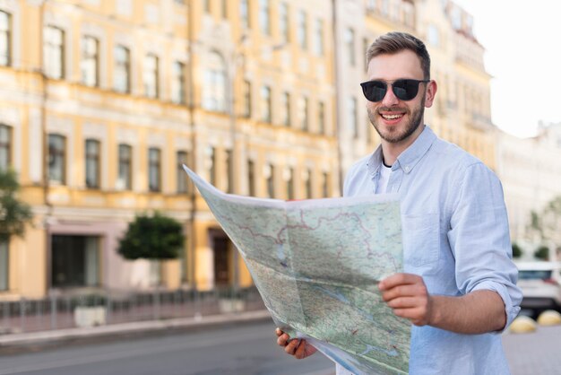 Vista frontal del hombre turístico sonriente con mapa