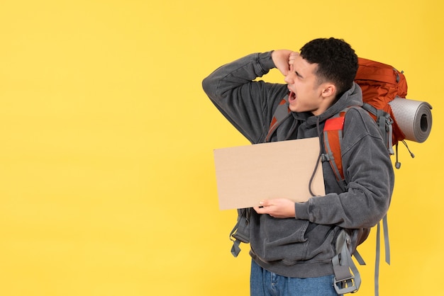 Vista frontal hombre viajero enojado con mochila con cartón