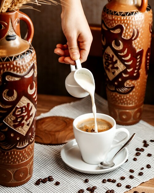 Vista frontal un hombre vierte crema en una taza de café espresso