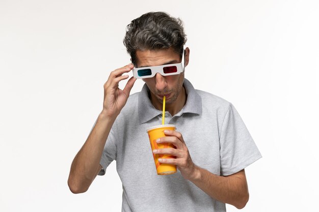 Vista frontal de hombres jóvenes bebiendo refrescos y con gafas de sol d sobre superficie blanca