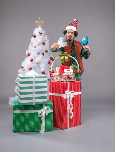 Vista frontal de los hombres jóvenes con billetes de avión en el escritorio de luz de regalo de Navidad humana año nuevo