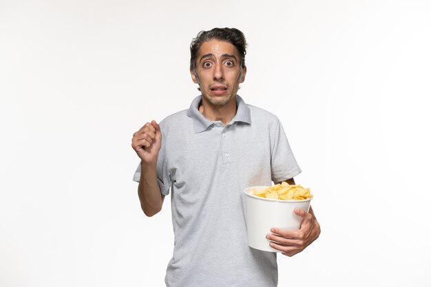 Vista frontal de los hombres jóvenes comiendo papas fritas viendo la película en el escritorio blanco