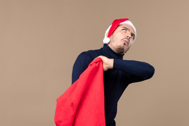 Vista frontal de los hombres jóvenes comprobando la bolsa actual sobre fondo marrón vacaciones de navidad santa