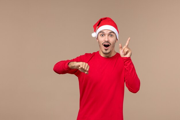 Vista frontal de los hombres jóvenes comprobando el tiempo sobre fondo marrón emociones vacaciones de navidad