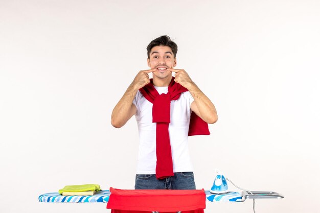 Vista frontal de los hombres jóvenes detrás de la tabla de planchar sonriendo en blanco