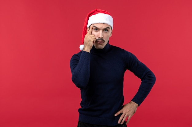 Vista frontal de los hombres jóvenes con gorro de año nuevo sobre el fondo rojo.