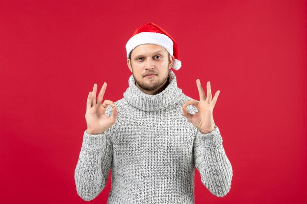 Vista frontal de los hombres jóvenes en jersey cálido en el color rojo de la mesa Navidad año nuevo nieve emoción vacaciones