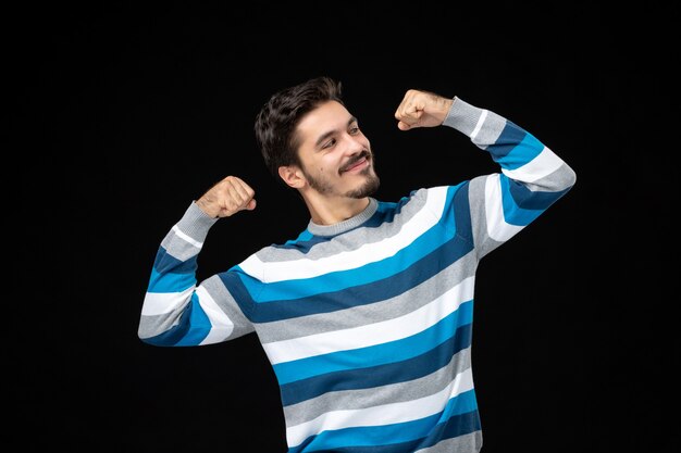 Vista frontal de los hombres jóvenes en jersey de rayas azules flexionando