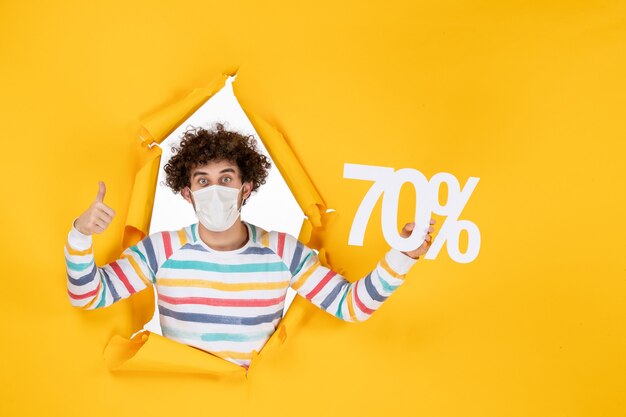 Vista frontal de los hombres jóvenes en la máscara con la escritura en la venta de color amarillo virus covid- fotos de compras