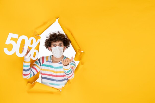 Vista frontal de los hombres jóvenes con máscara sosteniendo la escritura sobre el virus amarillo compras salud covid fotos venta pandemia de color