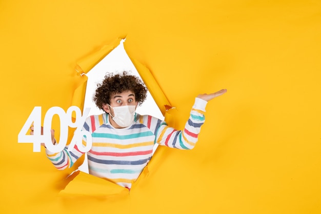 Vista frontal de los hombres jóvenes en máscara sosteniendo la escritura sobre el virus amarillo pandemia compras salud covid foto venta color