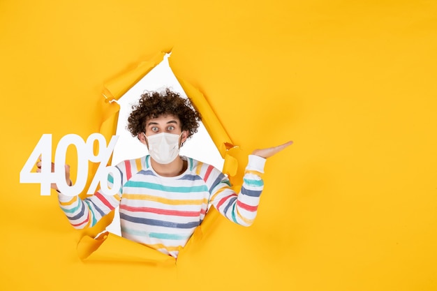 Vista frontal de los hombres jóvenes en la máscara sosteniendo la escritura sobre el virus amarillo pandemia compras salud covid foto venta colores