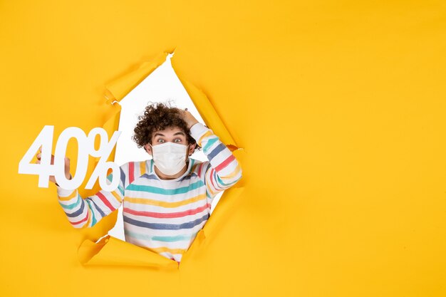 Vista frontal de los hombres jóvenes en máscara sosteniendo la escritura sobre el virus de la salud amarillo pandemia comercial covid- foto color