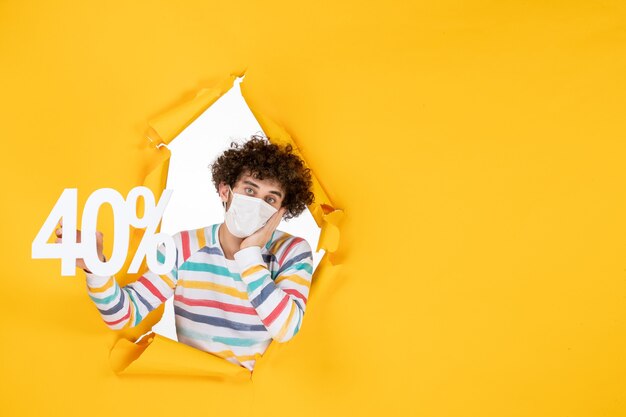 Vista frontal de los hombres jóvenes en máscara sosteniendo la escritura sobre el virus de la salud amarillo pandemia comercial covid- foto venta color