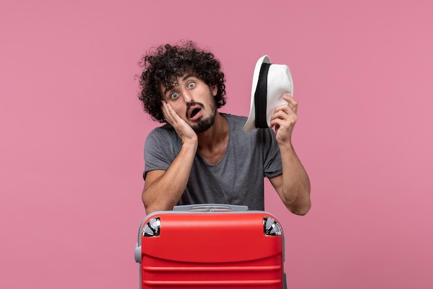 Vista frontal de los hombres jóvenes preparándose para las vacaciones en el escritorio rosa