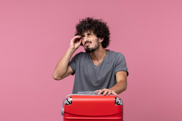 Vista frontal de los hombres jóvenes preparándose para el viaje en el escritorio rosa