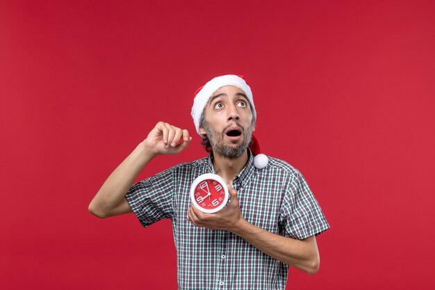 Vista frontal de los hombres jóvenes con relojes redondos en el escritorio rojo