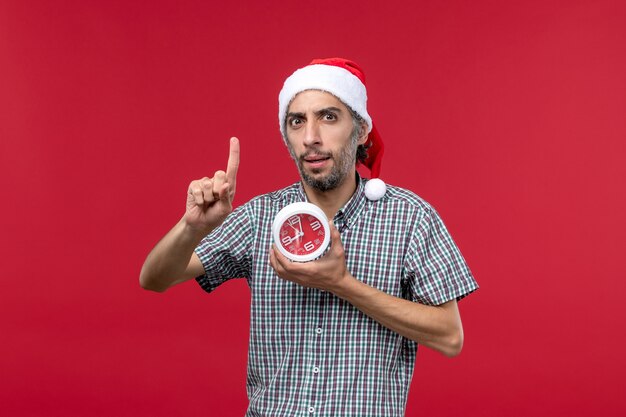 Vista frontal de los hombres jóvenes con relojes redondos en el escritorio rojo