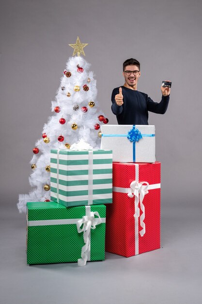 Vista frontal de los hombres jóvenes con tarjeta bancaria en el escritorio de luz año nuevo regalo de navidad