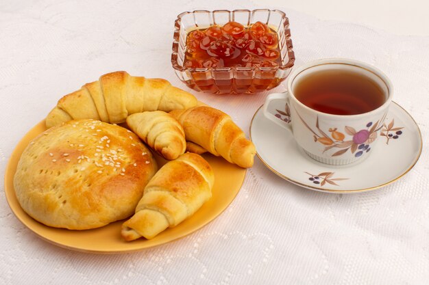 Vista frontal de la hora del té croissants galletas mermelada y té caliente en el piso blanco