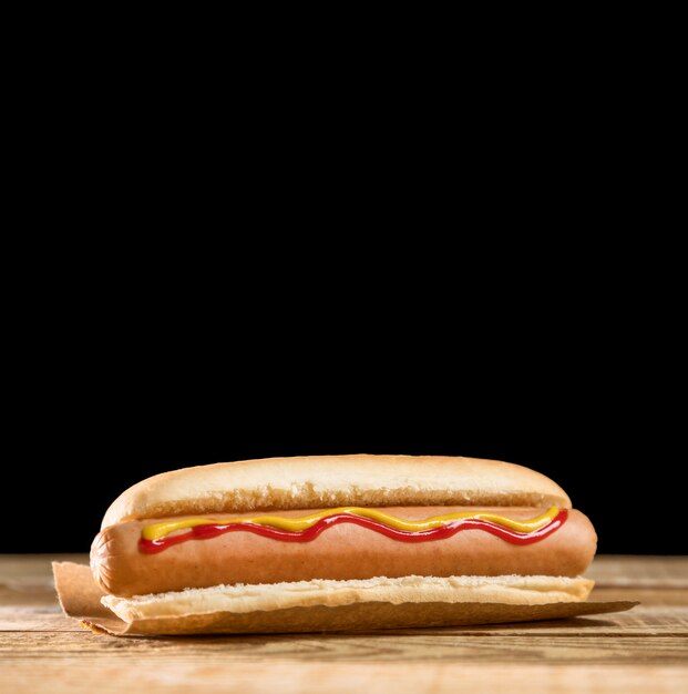 Vista frontal de hot dog y fondo negro del espacio de la copia