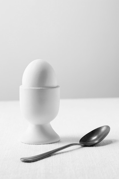 Vista frontal de huevo blanco en soporte con cucharadita