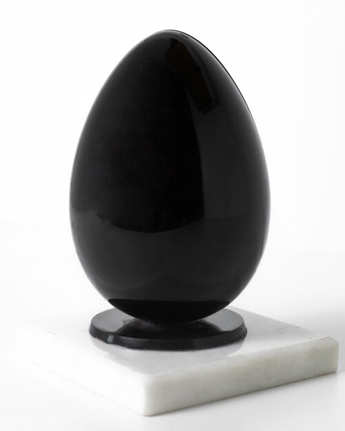 Vista frontal de huevo negro en el piso blanco