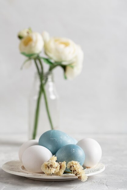 Vista frontal de los huevos de Pascua en un plato con flores en un jarrón