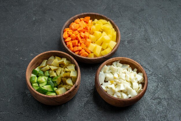 Vista frontal de los ingredientes de la ensalada en rodajas dentro de las ollas en la superficie oscura ensalada almuerzo snack vegetal