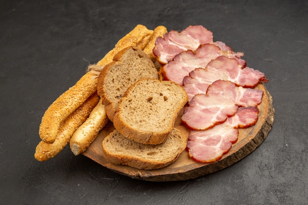 Vista frontal de jamón fresco en rodajas con rebanadas de pan y bollos en carne de color oscuro comida