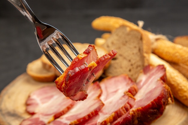 Vista frontal de jamón fresco en rodajas con rebanadas de pan y bollos en cerdo de comida de bocadillo de color oscuro