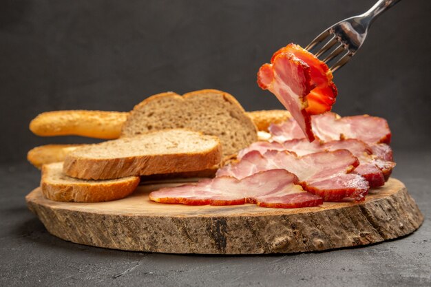 Vista frontal de jamón en rodajas con rebanadas de pan en el color gris oscuro de la comida del bocadillo de la carne del cerdo