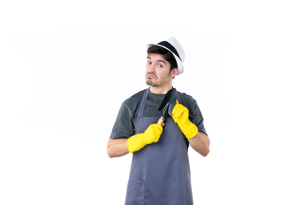 Vista frontal jardinero masculino en guantes amarillos sosteniendo una pequeña espátula sobre un fondo blanco flor árbol trabajo jardín arbusto color tierra trabajo de hierba