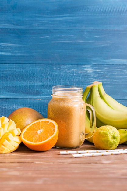 Foto gratuita vista frontal jarra de batido con plátanos y naranjas