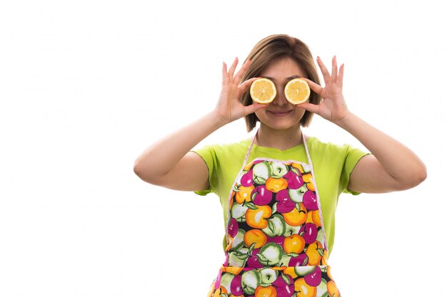 Una vista frontal joven ama de casa hermosa en camisa verde capa colorida celebración rodajas de naranja sonriendo sobre el fondo blanco limpieza de la casa cocina