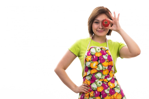 Una vista frontal joven ama de casa hermosa en camisa verde capa colorida con tomates rojos sonriendo sobre el fondo blanco limpieza de la casa cocina