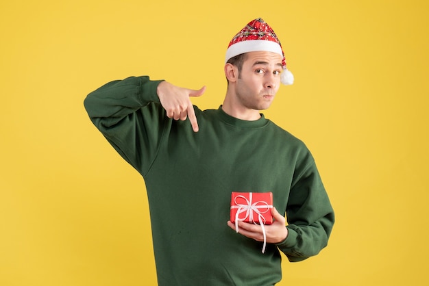 Vista frontal joven apuntando a su regalo en amarillo