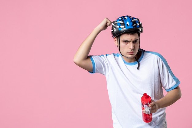 Vista frontal joven atleta en ropa deportiva casco y sosteniendo una botella de agua