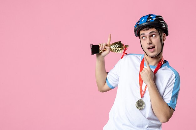 Vista frontal joven atleta en ropa deportiva con copa de oro y medalla