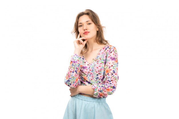 Una vista frontal joven y atractiva dama en camisa colorida flor diseñada y falda azul posando en el blanco