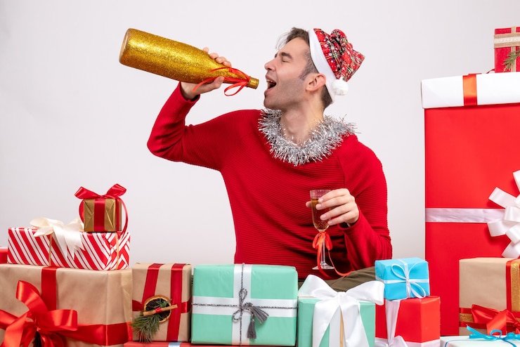 Foto gratuito vista frontal joven bebiendo champán sentados alrededor de regalos de navidad