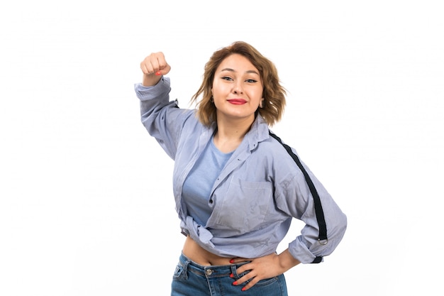 Una vista frontal joven y bella chica en camisa azul y blue jeans sonriendo preparándose para golpear en el blanco