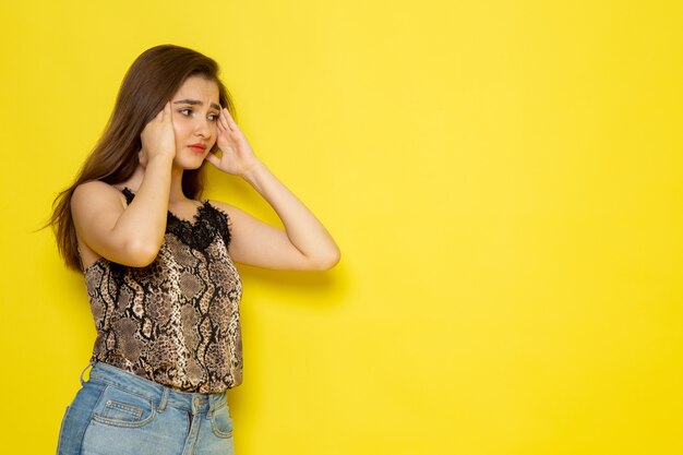 Una vista frontal joven y bella dama en blusa marrón y jeans azul con dolor de cabeza