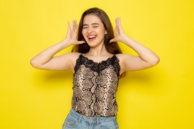 Una vista frontal joven bella dama en blusa marrón y jeans azul sonriendo