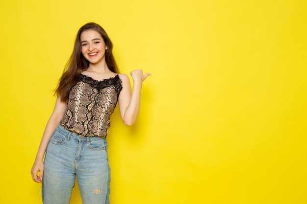 Una vista frontal joven bella dama en blusa marrón y jeans azul sonriendo