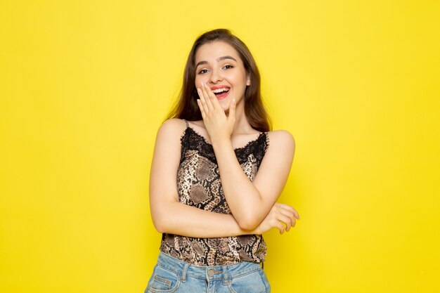 Una vista frontal joven bella dama en blusa marrón y jeans azul sonriendo