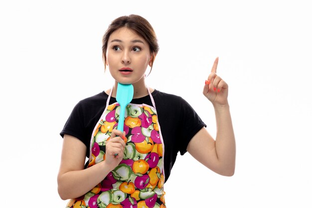 Una vista frontal joven y bella dama en camisa negra y capa colorida con electrodomésticos de cocina azul pensando