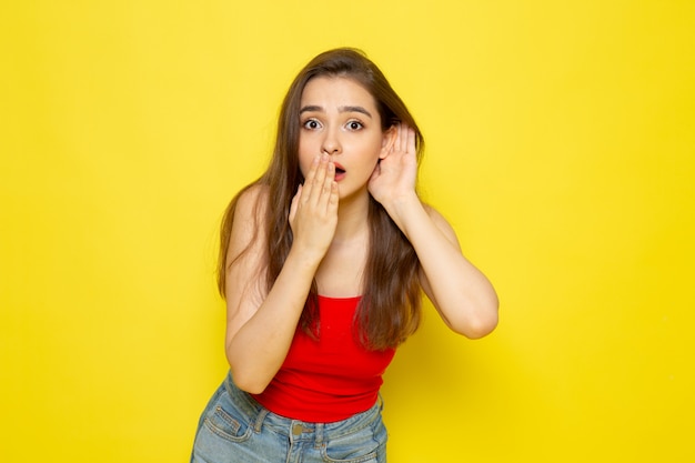 Una vista frontal joven bella dama en camisa roja y jeans azul con expresión de sorpresa